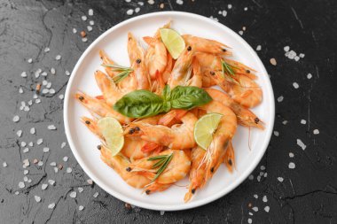 Pişirme arka planı ya da deniz ürünleri konsepti için siyah yüzeyde otlu karides ve kaba tuz