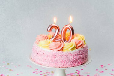 Pembe şekerli bir pasta ve iki mum doğum günü kutlamasını bekliyor..