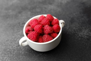 Meyve tatlısı için siyah arka planda beyaz kasede ahududu ya da temiz yemek kabı