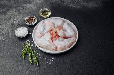 Baharatlı baharatlı tavuk kanatları ve koyu taşlı arka planda yağ.