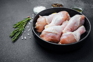 Siyah kasede çiğ tavuk budu ve baharat.