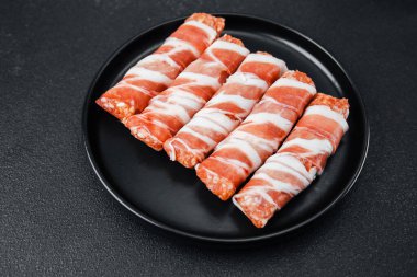 Siyah tabağa sarılı domuz pastırmasının üst görüntüsü.