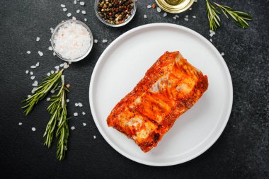 Beyaz tabakta marine edilmiş domuz pirzolası ve baharat.