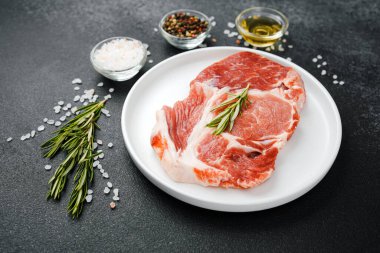 Biberiye ve baharatlı, beyaz tabakta pişmemiş biftek.