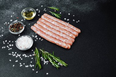 Siyah taş masada baharatlı çiğ sosisler.