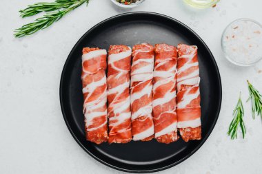 Domuz pastırması siyah tabakta baharat ve biberiye ile sarılmış.