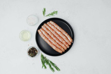 Siyah tabakta taze domuz sosisi, biberiye ve tuz.