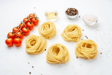 Beyaz arka planda domates ve baharatlı çiğ tagliatelle makarnası.