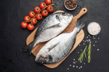 Domates baharatlı taze çiğ dorado balığı ve koyu arkaplanda tuz.