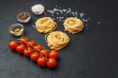Domatesli Tagliatelle makarnası, yağ, biber ve tuz siyah desenli arka planda.