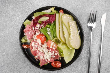 Yemek planı veya vejetaryen yemek balosu için çatal bıçaklı armut peynirli salata üst görünümü