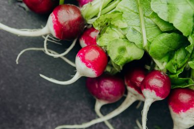 Siyah arka planda yeşil yapraklı taze kırmızı turplar.