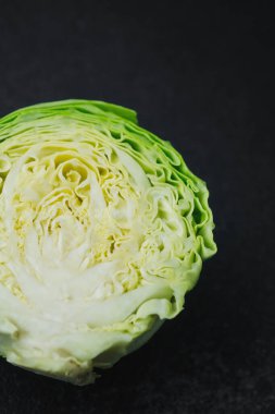 Siyah zemin üzerinde eşmerkezli yaprak katmanları olan yarım lahana.