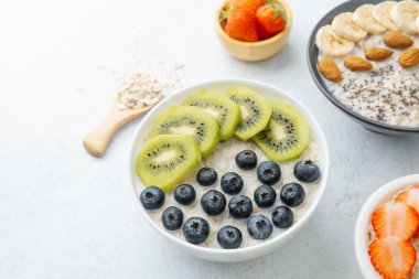 Beyaz yüzeyde meyve ve tahıllı yulaf ezmesi kaseleri.