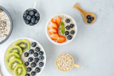 Beyaz arka planda meyveler ve yulaflı yulaf ezmesi kaseleri.