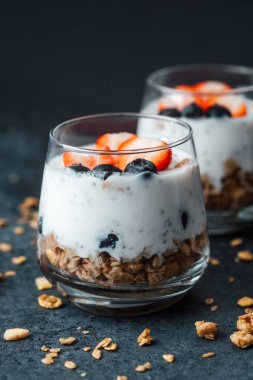 Yoğurtlu granola parfe, koyu arkaplanda çilek ve yabanmersini.