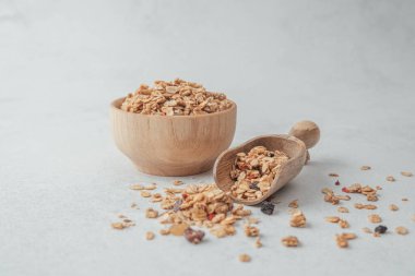 Tahta kasede granola ve açık gri arka planda kepçe