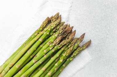 Temiz, aydınlık bir yüzey üzerinde pişmeyi bekleyen bir sürü taze kuşkonmaz..