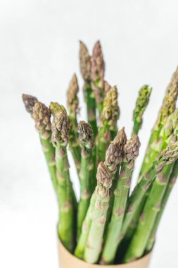 Hafif bir yüzeyde kırsal bir vazoda zarif bir şekilde dizilmiş bir grup yeşil kuşkonmaz..