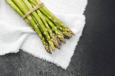 Beyaz bir mutfak havlusuna sarılı yeşil kuşkonmaz, pişirmeye hazır..