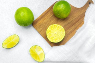 Parlak limonlar ve yarım kireç. Parlak bir mutfak ortamında ahşap bir tahtada oturuyorlar..