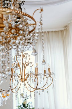 Kristallerle süslenmiş göz kamaştırıcı bir altın avize iyi aydınlatılmış bir alanı aydınlatır..