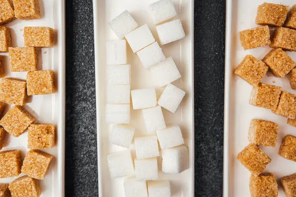 Dikdörtgen tabakalarda sıralanmış çeşitli şeker küpleri farklılıklarını vurgular.