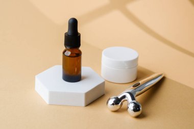 Kahverengi cam damlalar, gümüş yüz silindirleri ve beyaz kavanozlar kaidede sergileniyor.