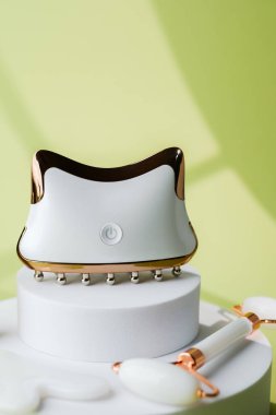 Yeşim silindirli ve gua sha taşlı elektronik yüz masajcısı.