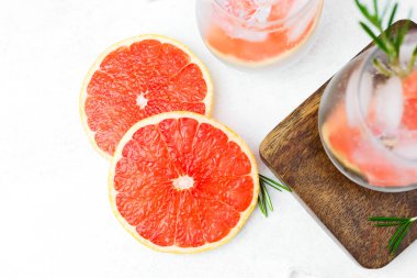 Biberiyeli greyfurt kokteyli ve narenciye dilimleri ve köpüklü sıvı içeren buz.