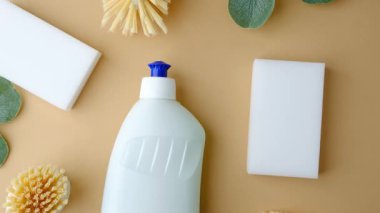 Hafif arka planda sünger ve fırçalı bir şişe temizlik sıvısı..