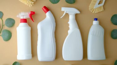 Açık kahverengi zemin üzerinde fırça ve yeşil yapraklı beyaz temizlik şişeleri grubu