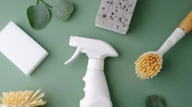 Yeşil bir yüzey üzerinde bitkilerle temizlik yapmak için beyaz sprey, sünger ve fırçalar.