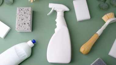 Yeşil bir yüzeye serilmiş beyaz temizlik spreyi, sünger ve fırça..