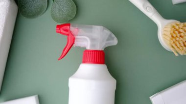 Beyaz sprey şişesi ve yeşil yapraklı temizlik fırçası..