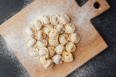 Tahta üstünde un tozlu çiğ kapel makarnası.