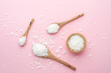 Ahşap kaşık soya gevreği ve kase pembe arka planda dağınık gevrek.