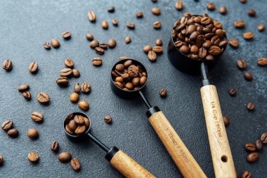 Koyu arkaplanda kaşık ölçmede kahve çekirdekleri