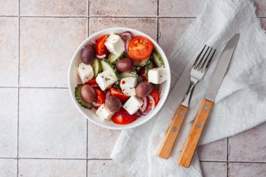 Çatal ve bıçakla fayans zemininde Yunan salatası