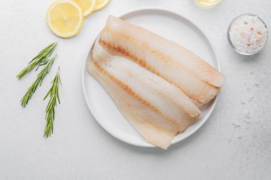 Beyaz arka planda limonlu ve biberiyeli ham pollock fileto.