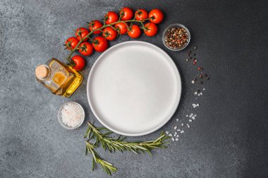 Boş beyaz tabak, zeytinyağı biberiye biber, tuz ve kiraz domatesli koyu masa.