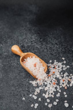 Koyu arkaplanda pembe himalaya tuzu olan ahşap kepçe.