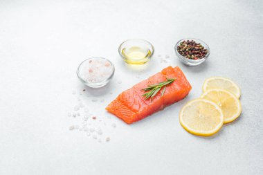 Biberiye, tuz, limon dilimleri ve biberle süslenmiş somon filetosu pişirmeye hazır..