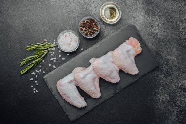 Siyah tahtada çiğ tavuk kanadı ve baharat.