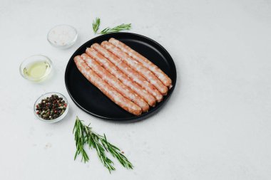 Siyah tabakta taze domuz sosisi, biberiye ve tuz.