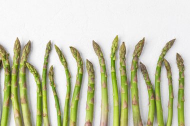Beyaz arkaplanda fotokopi alanı ile sıralanmış yeşil kuşkonmaz mızrakları