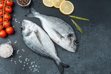 Limon biberli çiğ dorado balığı ve siyah arka planda biberiye.