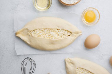 Işık yüzeyinde peynirli ve yumurtalı iki çiğ khachapuri.