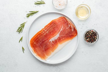 Biberiye ve tuzlu beyaz tabakta jambon dilimleri.