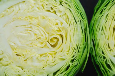 Karanlık arka planda iki kesik lahana parçası. Yakın plan.